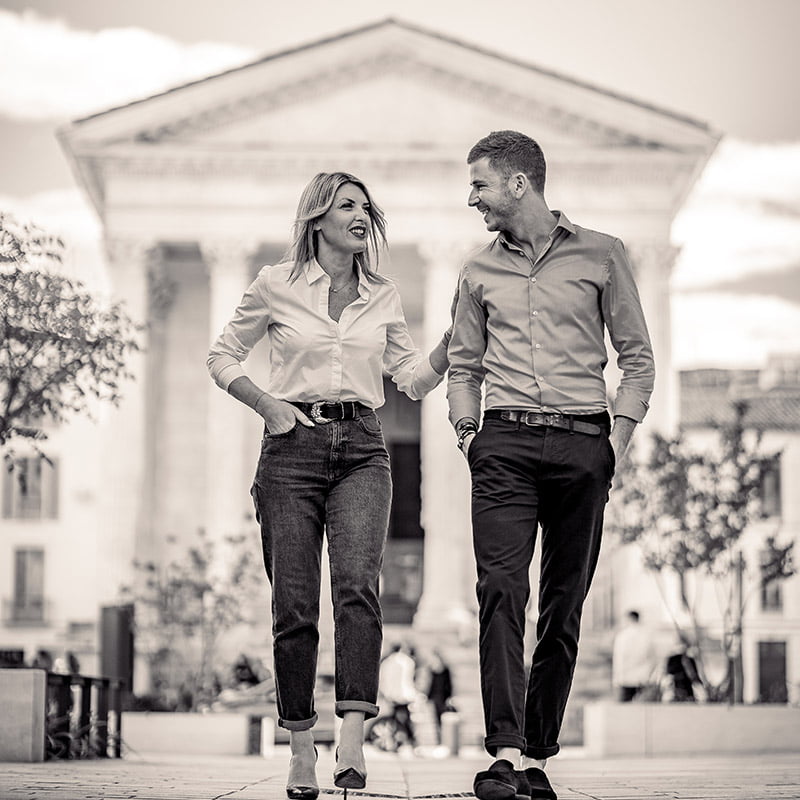 Photo en noir et blanc, des deux associés de L'Agence, aux pieds de la Maison Carrée à Nîmes