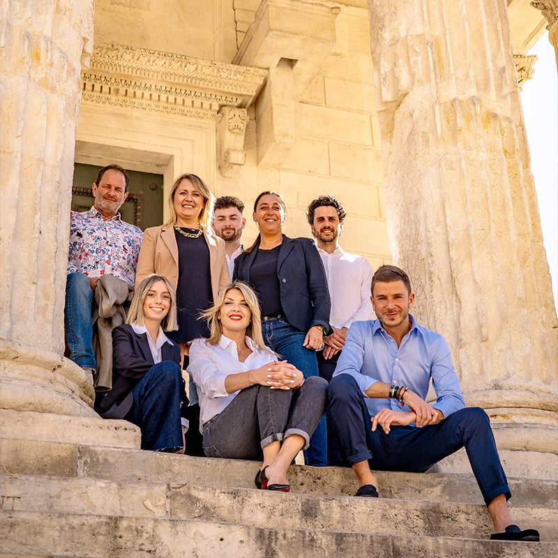 Photo de l'équipe de L'Agence, sur les marches de la Maison Carrée à Nîmes